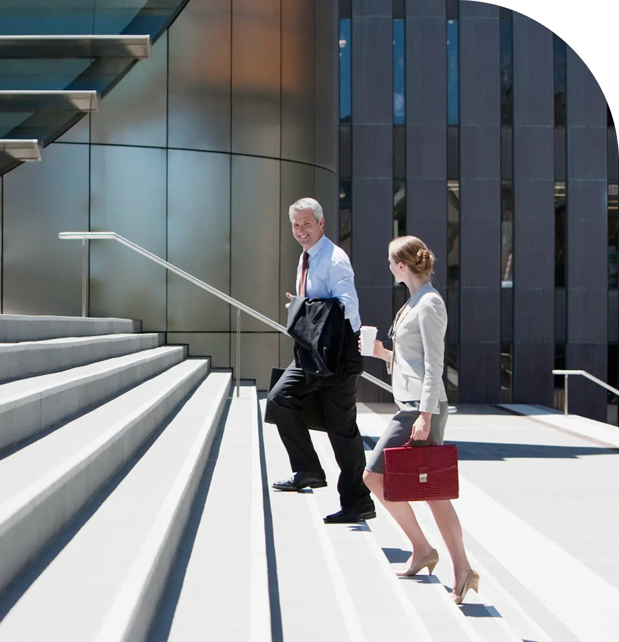 Colleagues discussing ideas while ascending a spiral staircase in a contemporary office building with natural light.