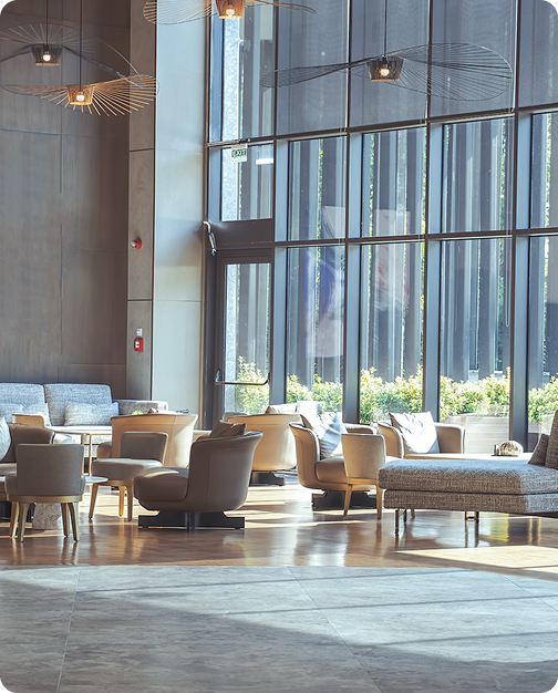 Upscale commercial lobby with designer furnishings, statement lighting, and natural light from tall windows overlooking trees.